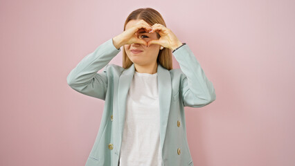 Wall Mural - Young blonde woman business worker smiling confident doing heart gesture over isolated pink background