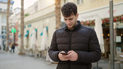 Canvas Print - Young hispanic man using smartphone at coffee shop terrace