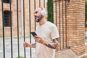 Poster - Young bald man listening to music and dancing with serious expression at street