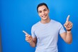 © Krakenimages.com - Young hispanic man standing over blue background smiling confident pointing with fingers to different directions. copy space for advertisement