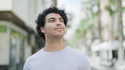 Canvas Print - Young latin man smiling confident looking to the sky at street