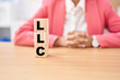 © Krakenimages.com - Business woman holding cubes with llc word on the table