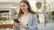 © Krakenimages.com - Young hispanic woman using smartphone smiling at coffee shop terrace
