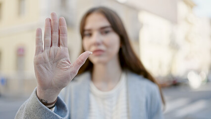 Poster - Young hispanic woman doing stop gesture with hand at street