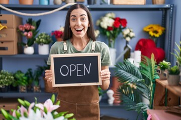 Sticker - Young brunette woman working at florist holding open sign celebrating crazy and amazed for success with open eyes screaming excited.