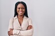 © Krakenimages.com - African woman with braids standing over white background happy face smiling with crossed arms looking at the camera. positive person.