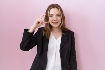 Sticker - Young caucasian business woman wearing black jacket smiling and confident gesturing with hand doing small size sign with fingers looking and the camera. measure concept.