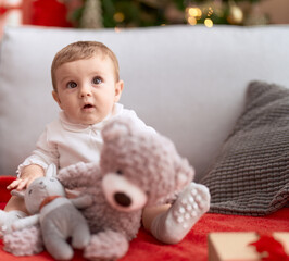 Sticker - Adorable toddler sitting on sofa with relaxed expression holding teddy bear at home