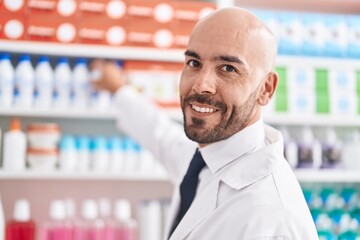 Sticker - Young bald man pharmacist smiling confident holding bottle of shelving at pharmacy