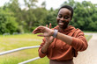 © Jelena Stanojkovic - Black woman runner, smartwatch and rest for breathing, heart rate or health while training in summer. Woman, running and healthcare tech for exercise, workout and fitness at nature park.