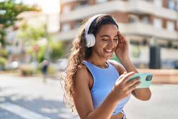 Wall Mural - Young beautiful hispanic woman smiling confident watching video on smartphone at street