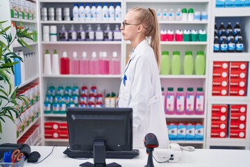 Poster - Young caucasian woman working at pharmacy drugstore looking to side, relax profile pose with natural face with confident smile.