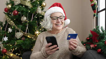 Wall Mural - Middle age woman with grey hair doing christmas online shopping with smartphone at home
