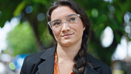 Young beautiful hispanic woman business worker smiling confident wearing glasses at park