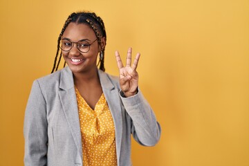 Poster - African american woman with braids standing over yellow background showing and pointing up with fingers number three while smiling confident and happy.