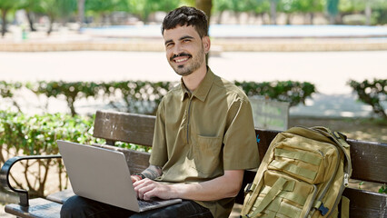 Sticker - Young hispanic man tourist using laptop sitting on bench at park