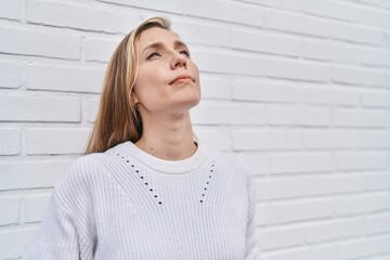 Canvas Print - Young blonde woman looking to the sky with serious expression at street