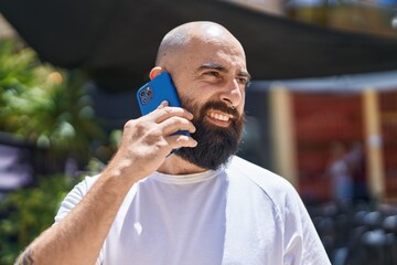 Young bald man smiling confident talking on the smartphone at street