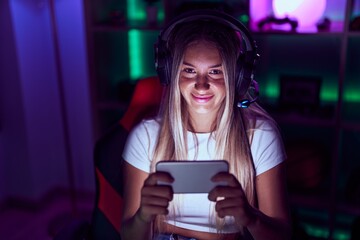 Poster - Young beautiful hispanic woman streamer playing video game using smartphone at gaming room