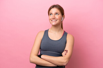 Wall Mural - Young sport caucasian woman isolated on pink background looking up while smiling