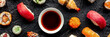 Sushi with soy sauce panorama. An assortment of rolls, maki, nigiri etc, overhead flat lay shot on a black background. Japanese restaurant