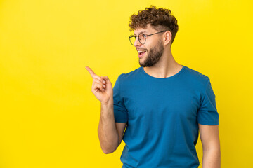 Wall Mural - Young handsome caucasian man isolated on yellow background intending to realizes the solution while lifting a finger up