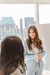 © Maria Vitkovska - Smiling businesswoman wearing formal suit talking near board with sticky notes