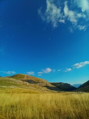 Canvas Print - Beautiful valley with hills and mountains in the background under the blue sky