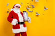Portrait of successful wealthy aged santa hold glass money jar flying dollar bills empty space isolated on yellow color background