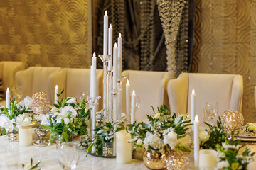 Wedding decorations. Served wedding table with decorative fresh white flowers, candles. Celebration details. Flower composition roses, plates, candles in candlesticks and balloons 