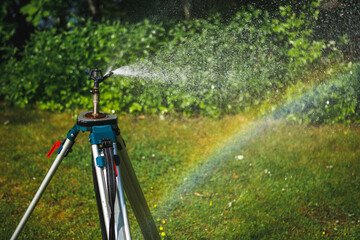 Wall Mural - garden sprinkler on a tripod watering new lawn