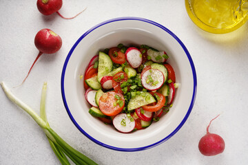 Wall Mural - spring salad of radishes, tomatoes, cucumbers, top view, light background, no people, close-up