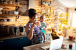 © Marko Geber - Multitasking African American Mother Working from Home with Baby