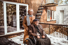 Senior Woman Pushing Disabled Husband In Winter Backyard