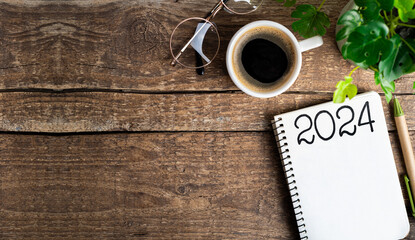 New year resolutions 2024 on desk. 2024 goals list with notebook, coffee cup, plant on wooden table. Resolutions, plan, goals, action, checklist, idea concept. New Year 2024 resolutions. Copy space