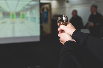 Process of shooting target at the shooting rifle range, women practicing with hand gun pistol at shooting gallery, firearms training, pointing weapon on digital screen, live fire digital targeting