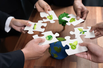 Cohesive group of business people holding eco icon jigsaw puzzle pieces around globe Earth as eco corporate responsibility for community and sustainable solution for greener Earth. Quaint