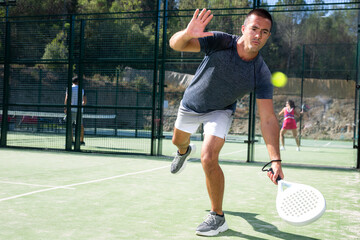 Wall Mural - Male padel tennis player training on court. Man using racket to hit ball.