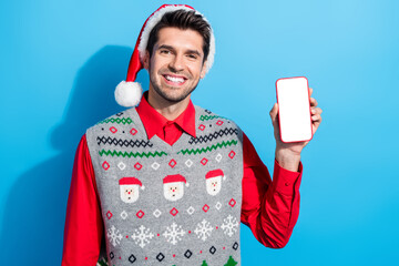 Poster - Photo of intelligent positive guy wear christmas hat demonstrate smartphone display qr code empty space isolated on blue color background