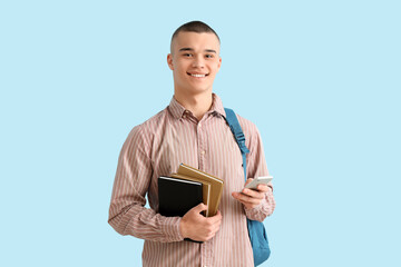 Wall Mural - Male student with backpack, books and mobile phone on blue background