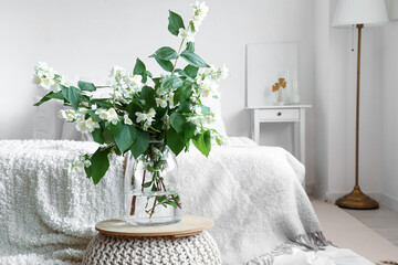 Poster - Vase with blooming jasmine flowers on pouf in interior of light bedroom