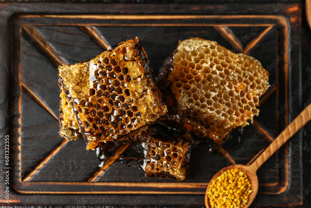 Wooden board with sweet honeycombs and bee pollen on table
