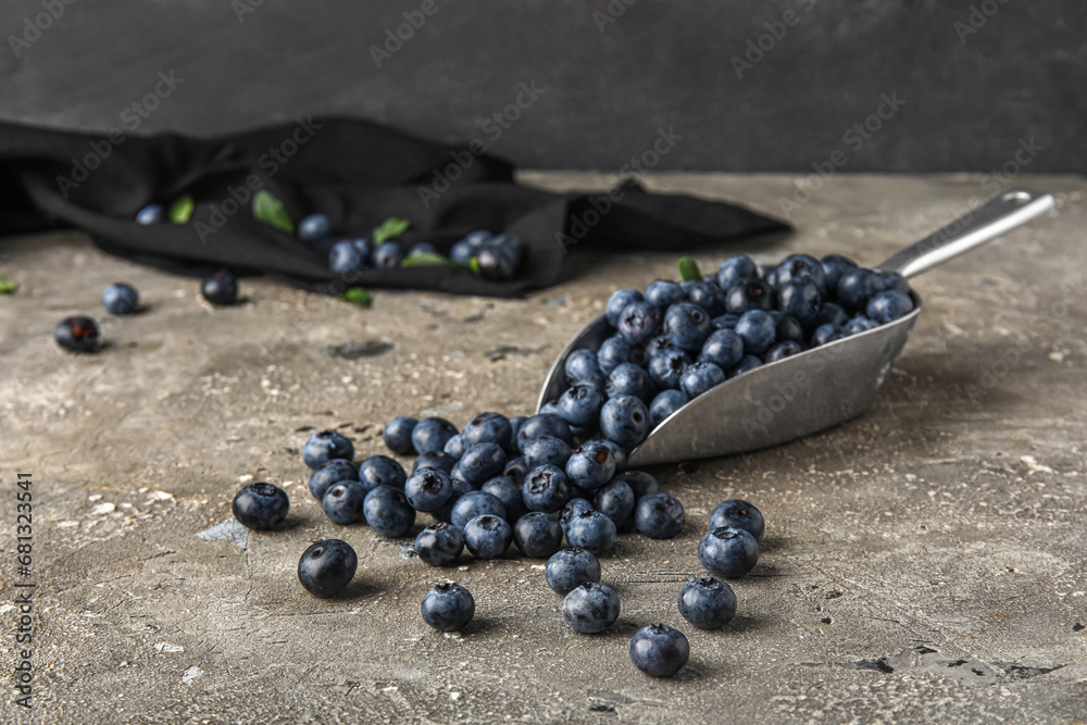 Metal scoop with fresh blueberries on grey table