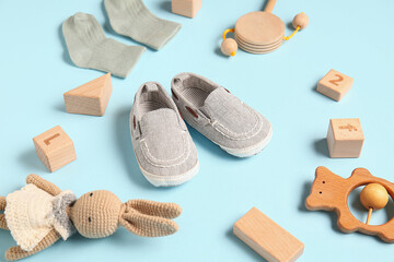 Wall Mural - Stylish baby shoes with socks and different toys on blue background