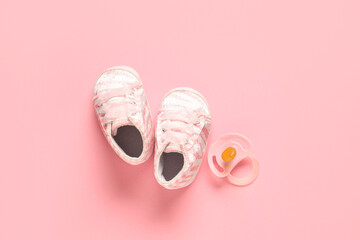 Wall Mural - Stylish baby shoes with pacifier on pink background