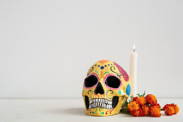 Poster - Candle with marigold flowers and painted skull on white background. Celebration of Mexico's Day of the Dead (El Dia de Muertos)