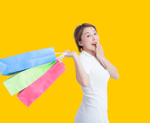 Asian happy female woman girl holds colourful shopping bags isolated on yellow background