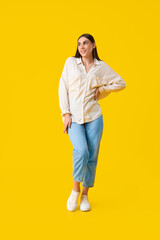 Sticker - Beautiful young woman in stylish white sneakers and cardboard box with high heels on yellow background