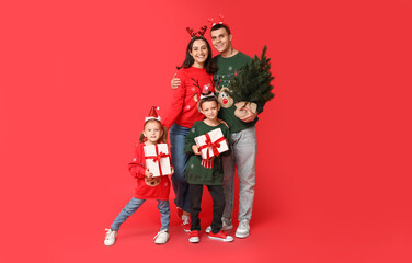 Canvas Print - Happy family in Christmas sweaters with gifts and tree on red background