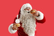 Leinwandbild Motiv Santa Claus with tasty burgers on red background
